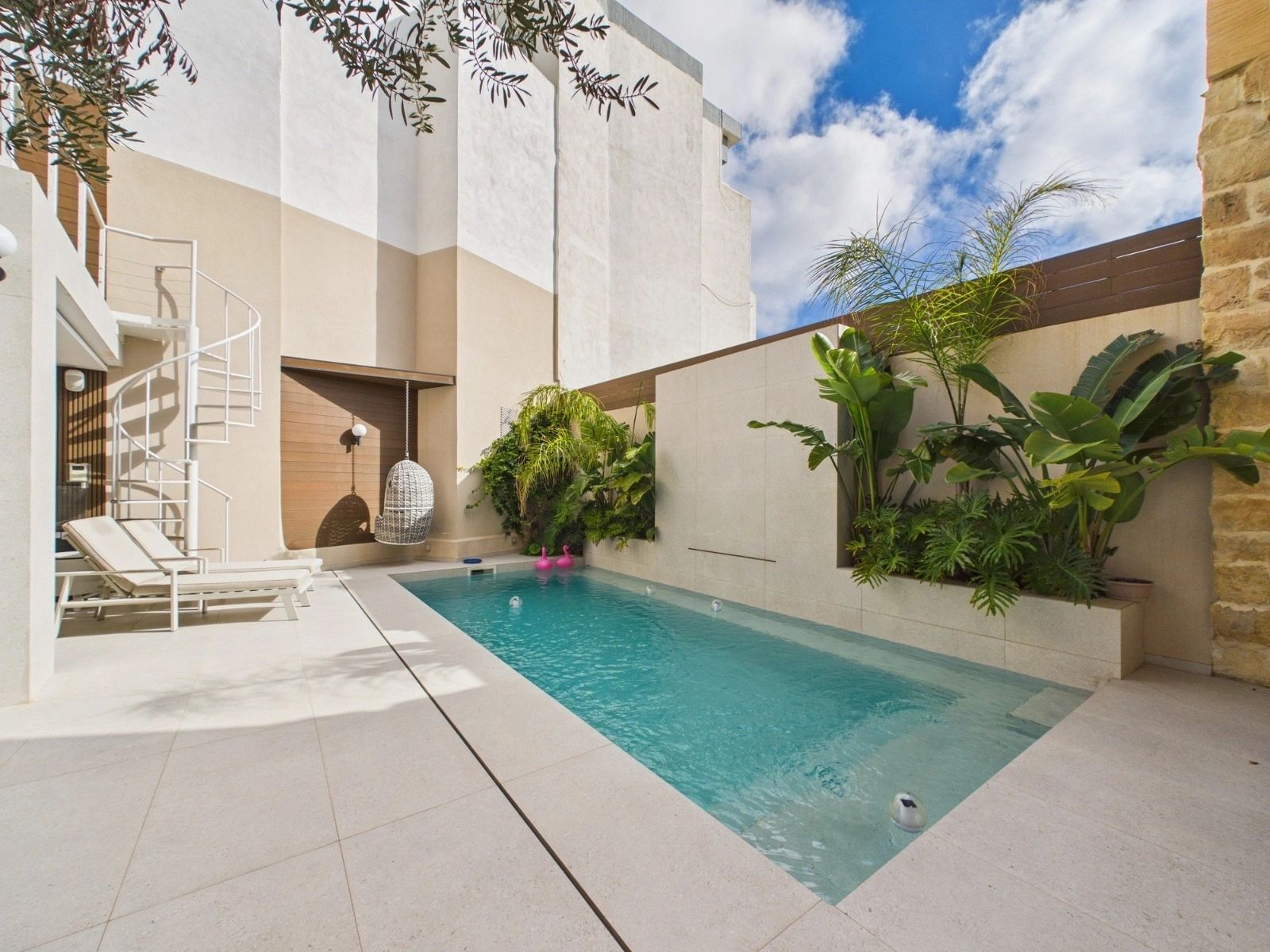 Heated swimming pool surrounded by limestone paving and tropical planting